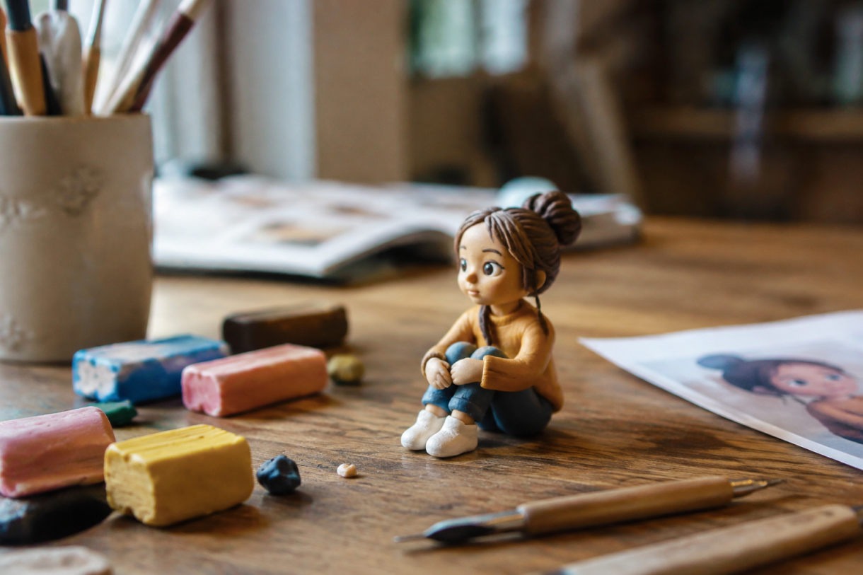 Modelage d'une figurine en pâte Fimo personnage à côté d'une impression 3D
